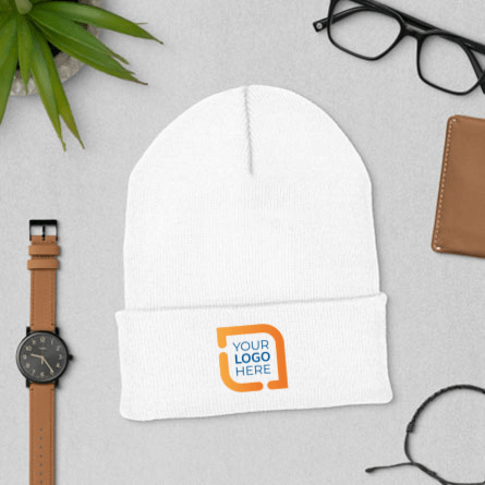 Lifestyle sample of the embroidered custom beanie surrounde with a watch, wallet, and other miscellanious items 