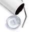Gefocuste afbeelding van de bovenkant van een roestvrijstalen beker die op de zijkant ligt met een stalen rietje en een plastic deksel naast de beker