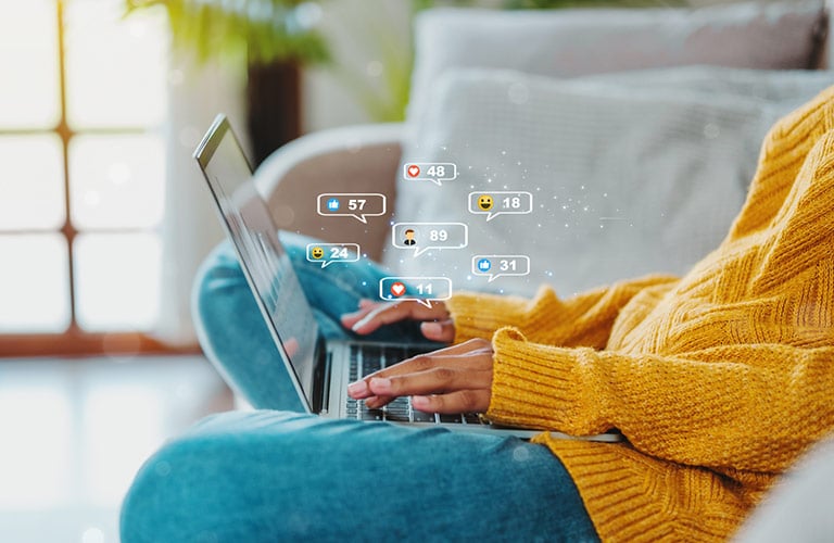 woman using laptop with social media logos
